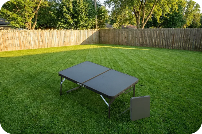 Quest Superlite Witney low table open on a lawn with a folded table beside it