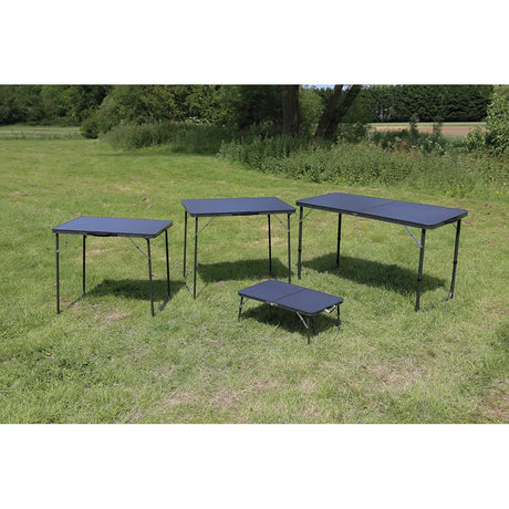 Four Quest camping tables on grass, with the low Witney table at the front for size comparison